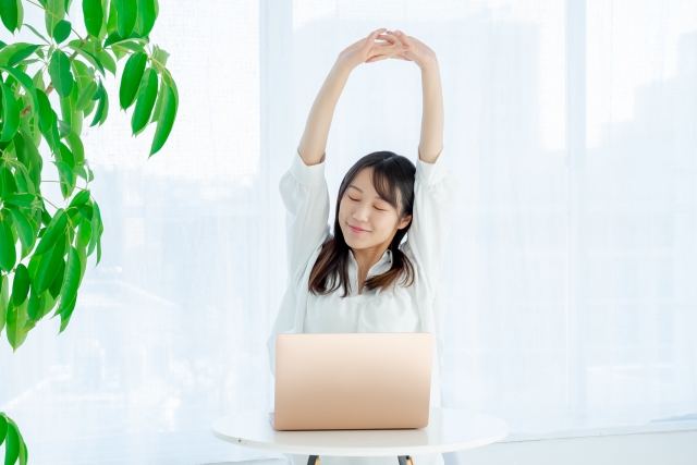 仕事の合間に伸びをして深呼吸をする女性