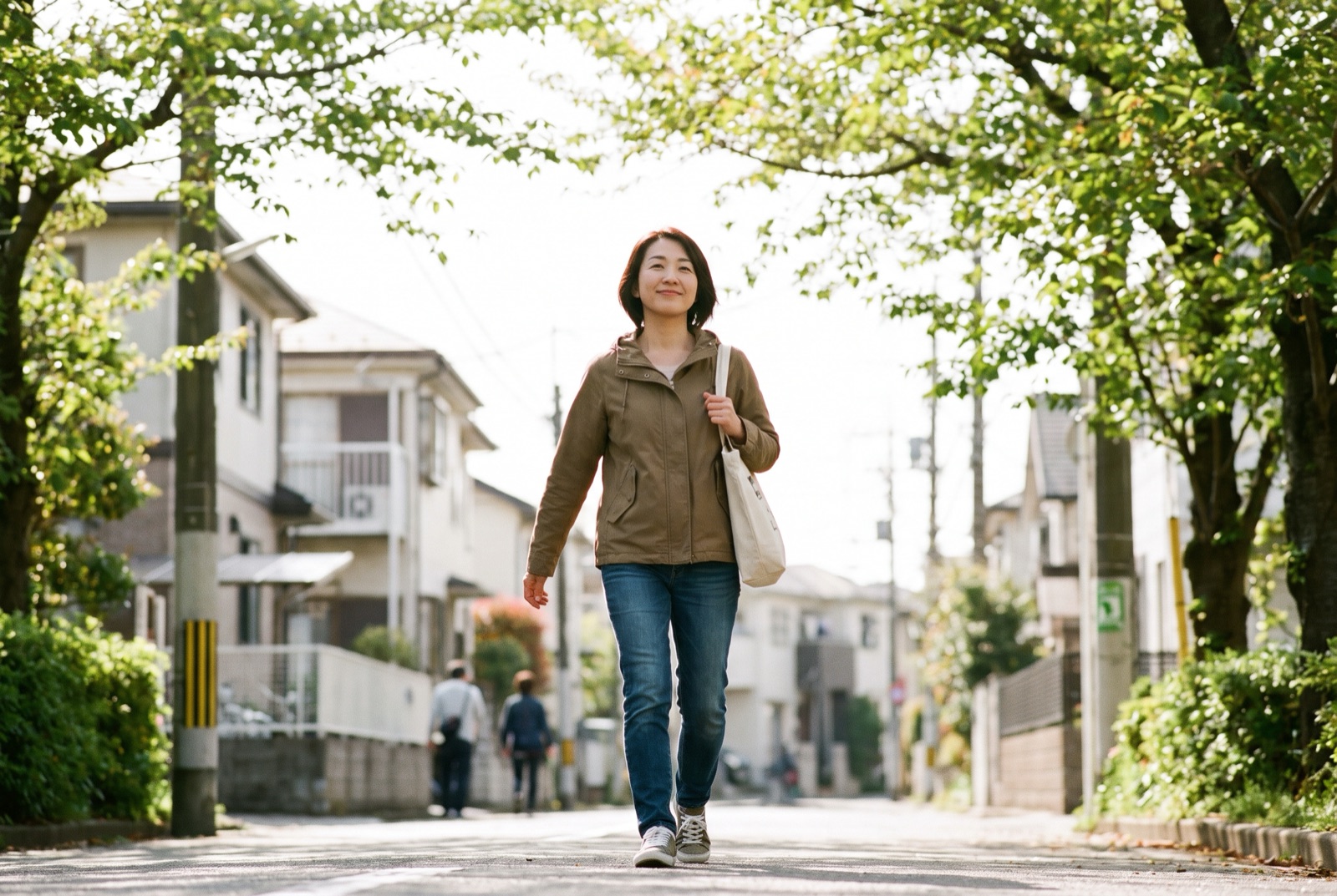 住宅街の歩道を少し早めに歩いている女性