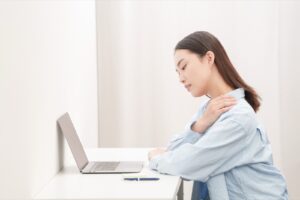 パソコン作業の途中で肩を押さえる女性
