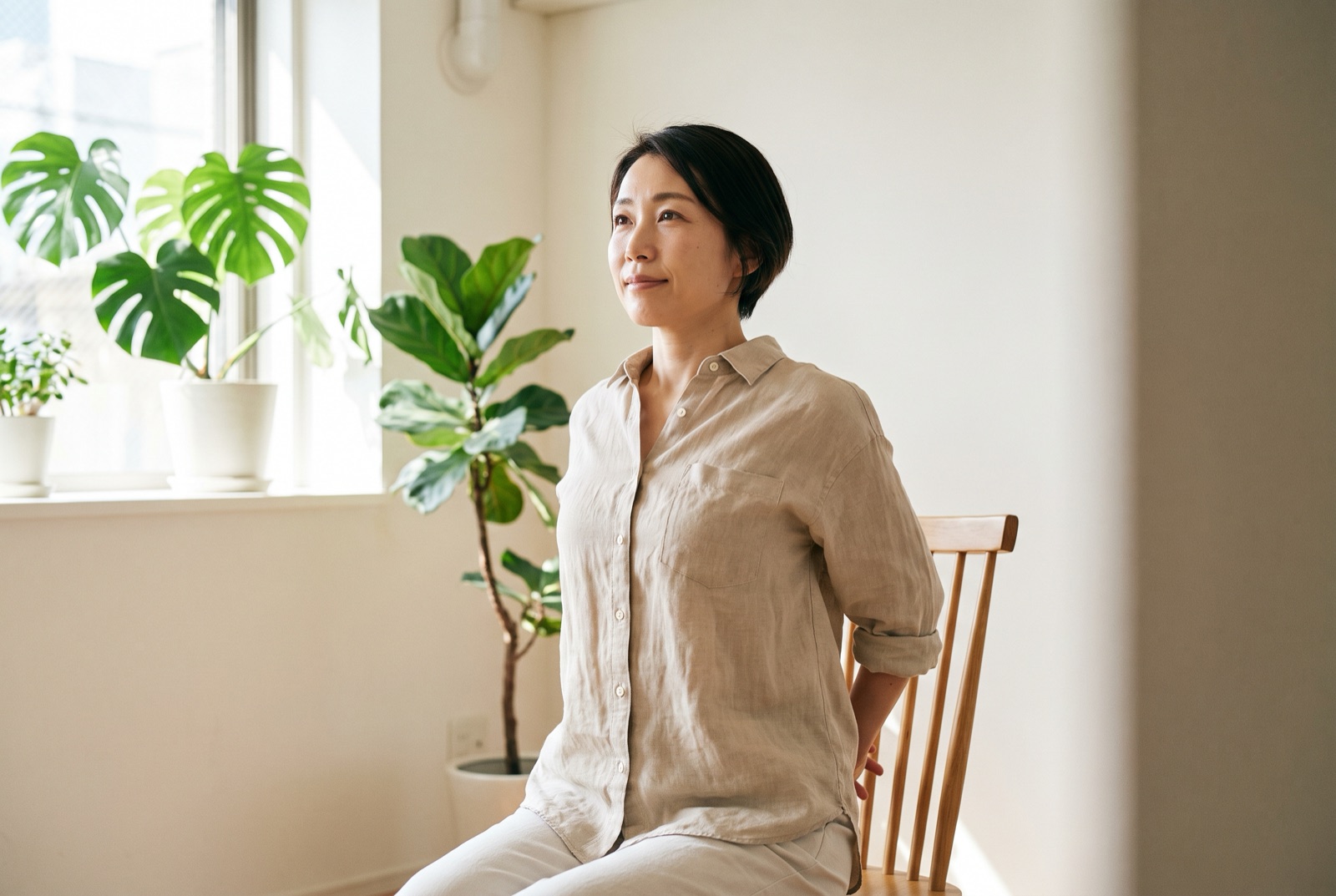 椅子に座って両手を後ろで組み、胸を開いている女性