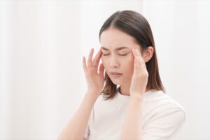 こめかみを押さえている女性