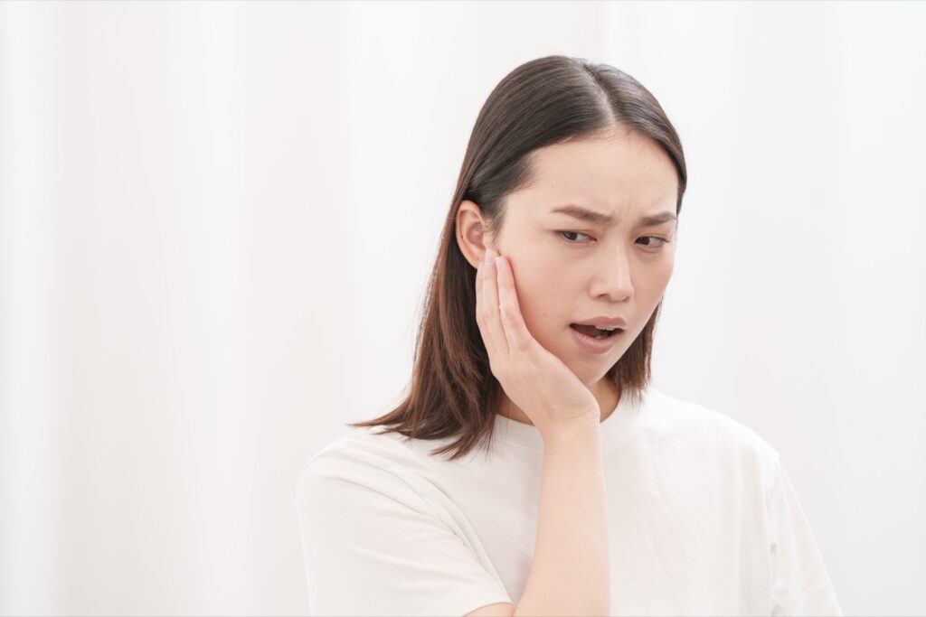 つらそうに頭のあたりを押さえている女性