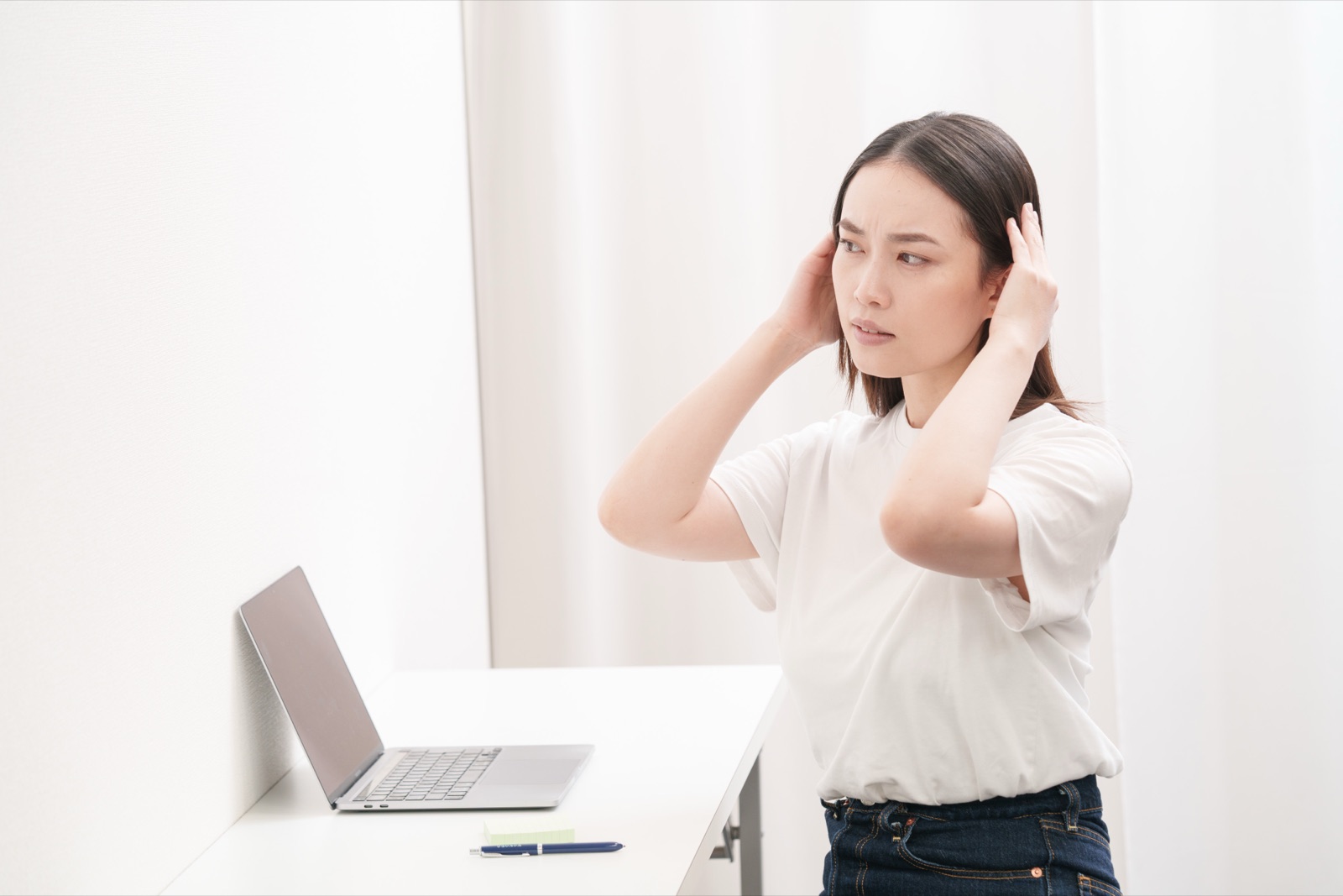 首の後ろに手を当てる女性