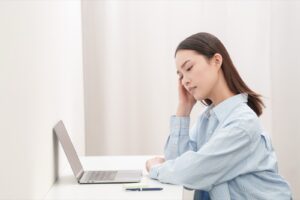 デスクワークの途中で肩を強く押さえる女性
