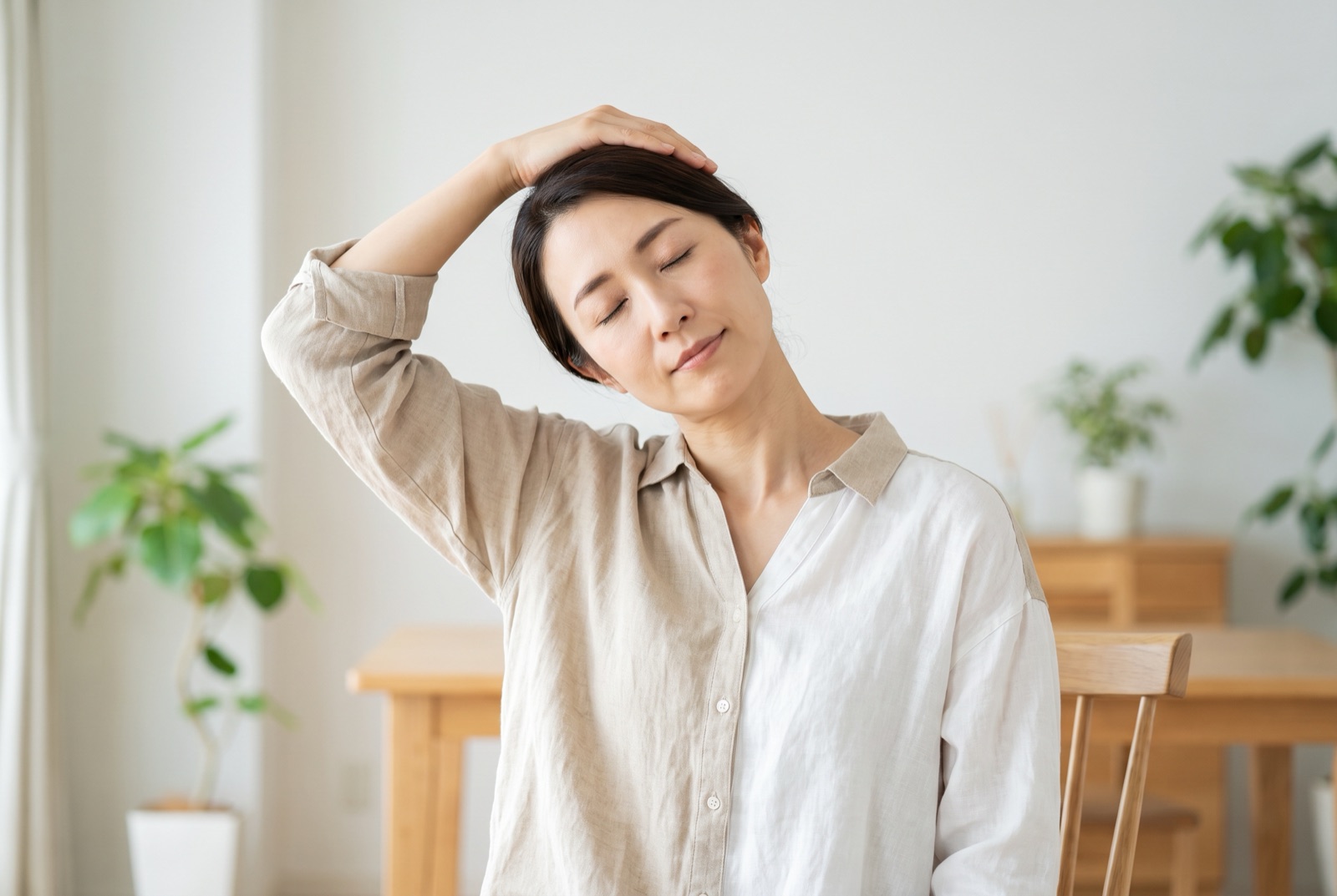 首を横に倒して首すじを伸ばしている女性