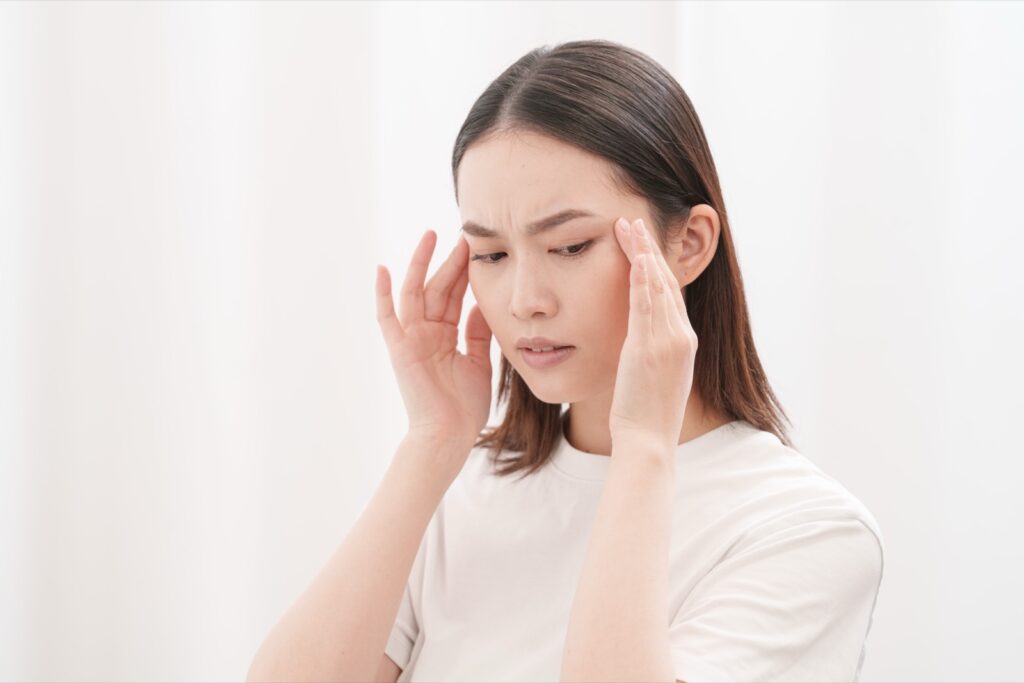 頭痛で悩み、こめかみを押さえる女性