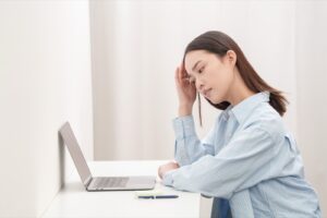 デスクワークの途中で額に手を当てる女性