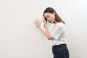 壁に手をついて、ふらつきを感じている女性