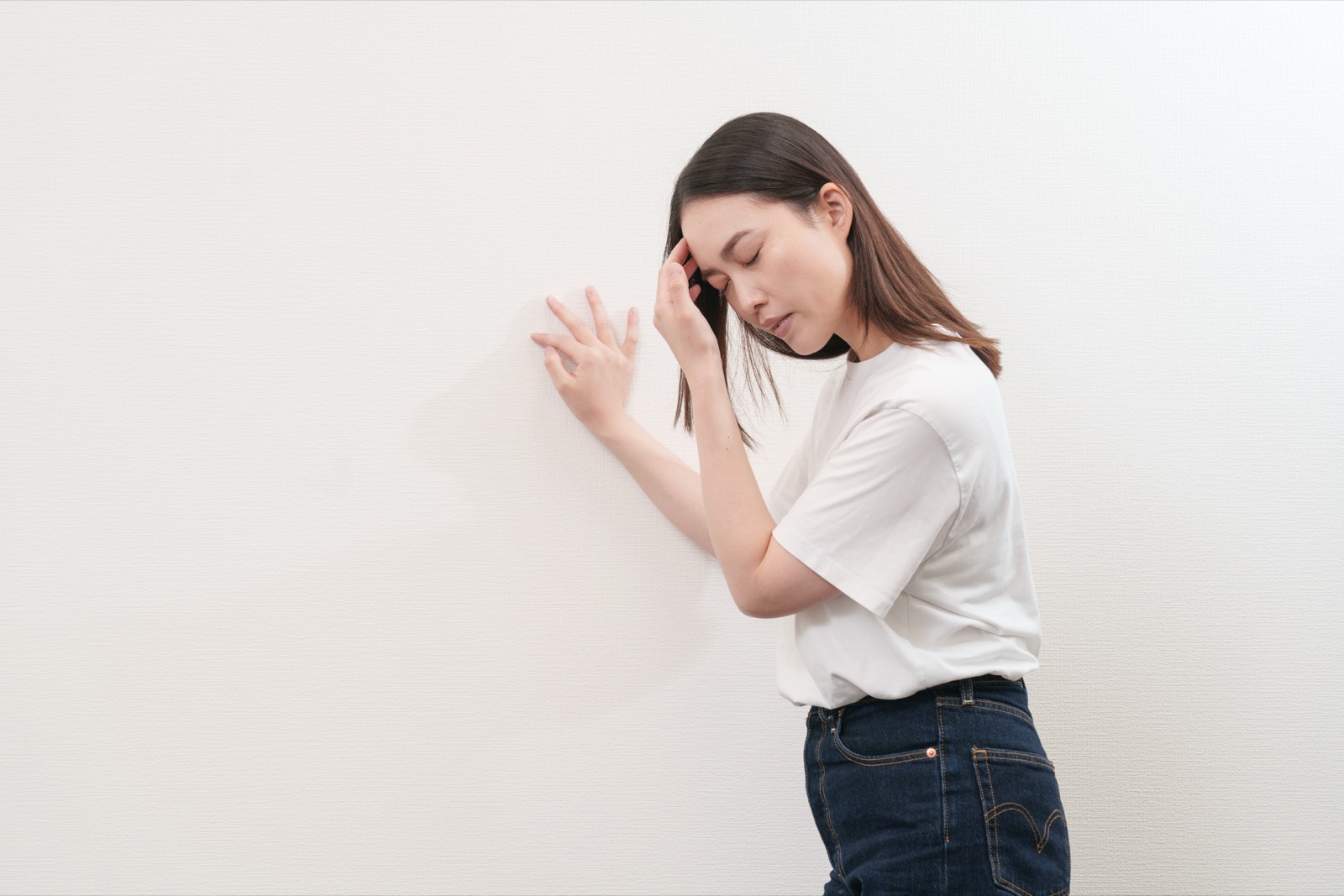 壁に手をついて、ふらつきを感じている女性