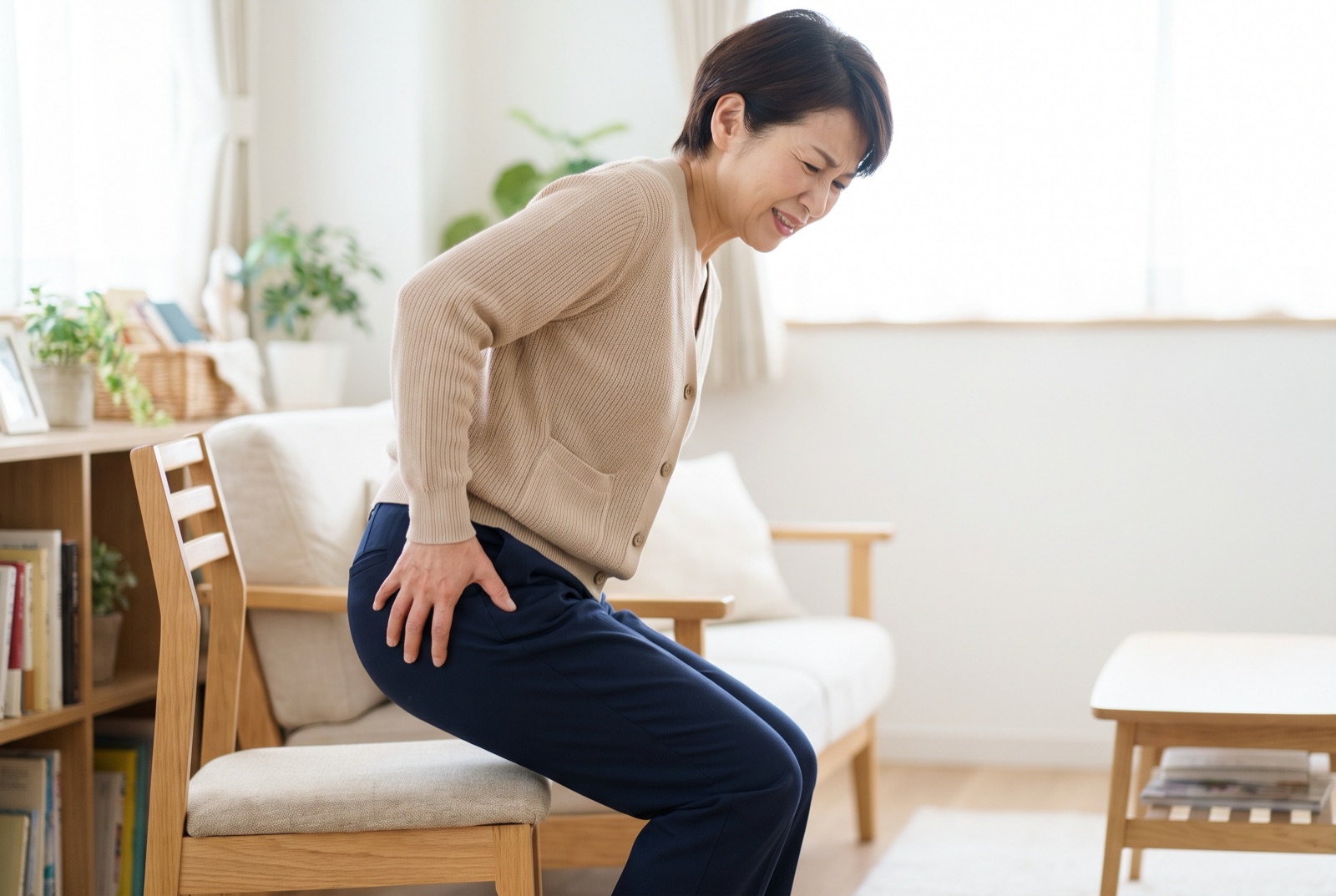椅子から立ち上がりかけて、太ももに手を当てる女性